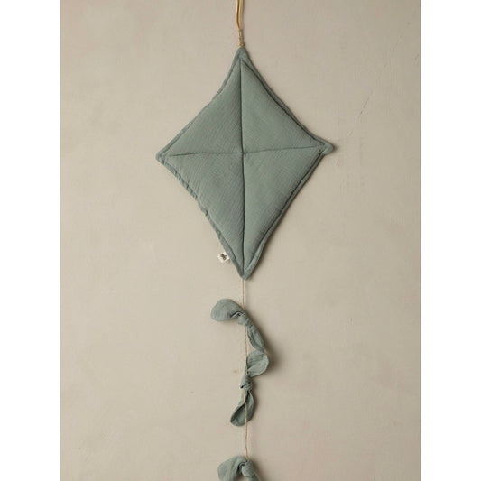 Decorative kite-shaped hanging with tassels on a beige wall