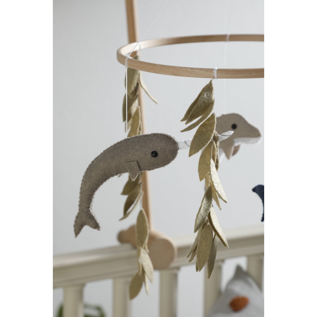 Baby mobile with dolphin shapes hanging from a gold circular frame against a white background.