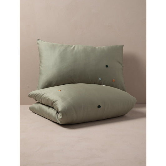 Green pillow and duvet set on a beige surface with a neutral background