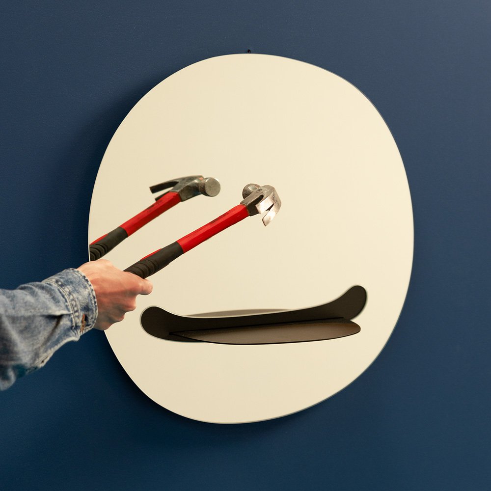Person holding a tool over a wall-mounted shelf with a blue background