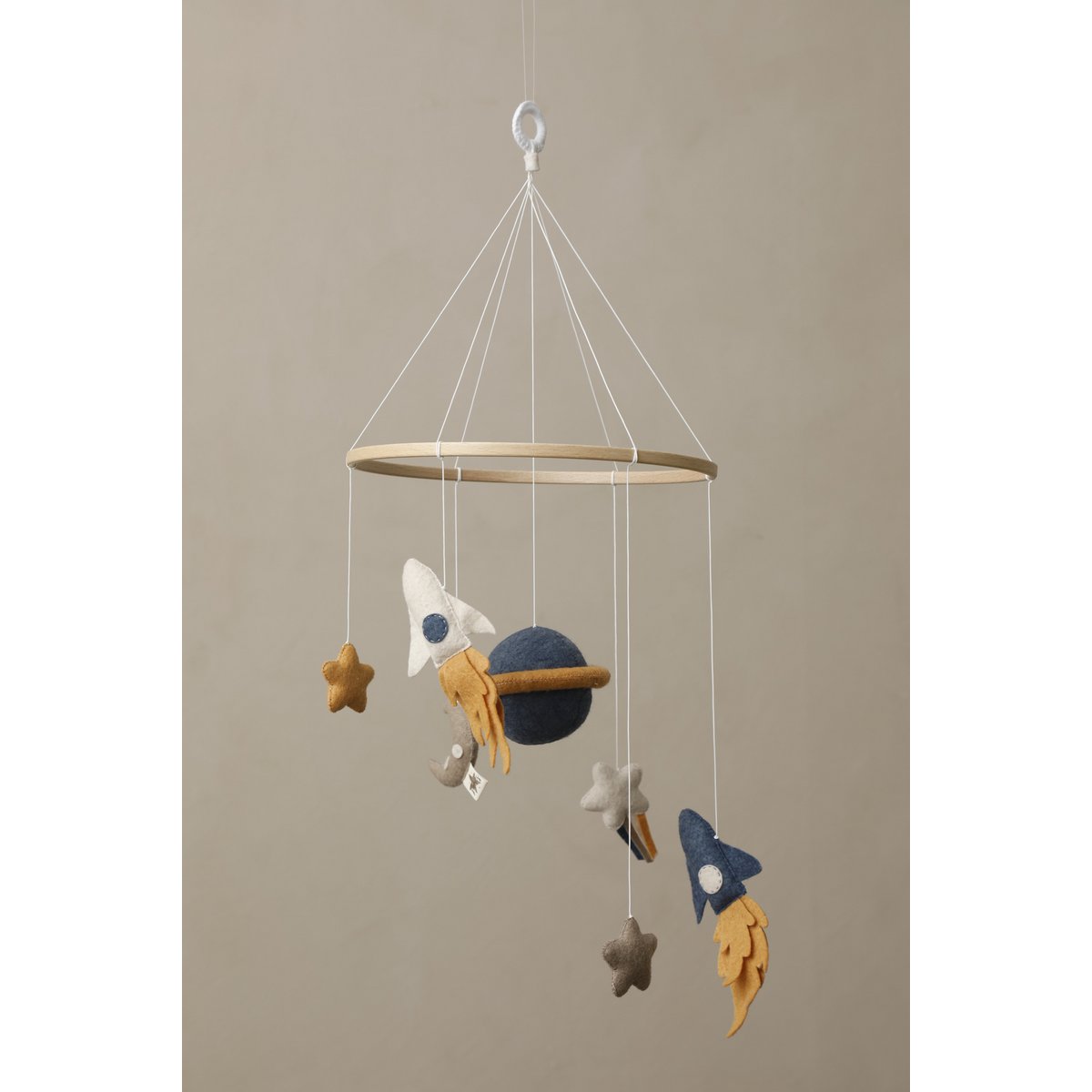 Children's mobile with space-themed decorations hanging against a beige background
