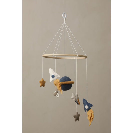 Children's mobile with space-themed decorations hanging against a beige background