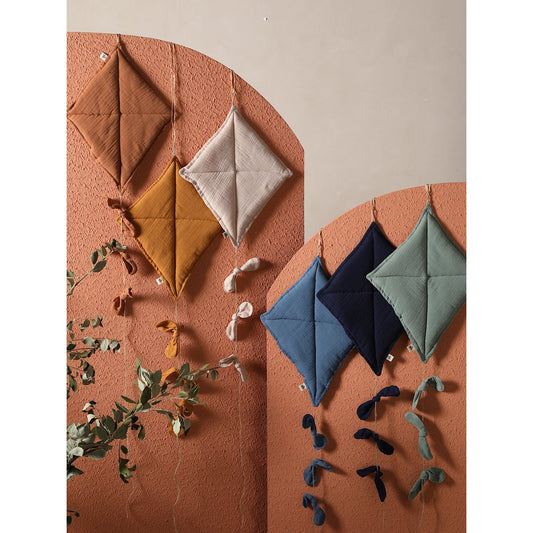 Colorful geometric fabric shapes on a textured surface with plants.