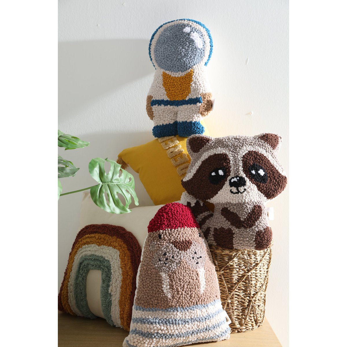 Three knitted or crocheted toys including a raccoon, a space-themed figure, and a striped animal on a light background.