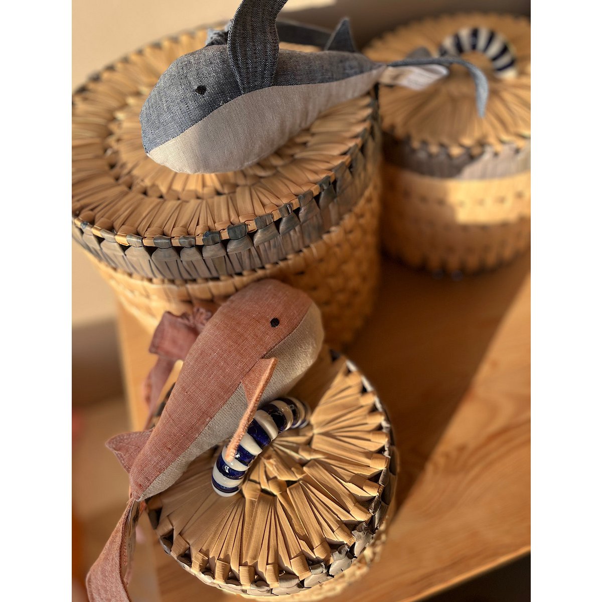 Woven baskets with toy whales on a wooden surface