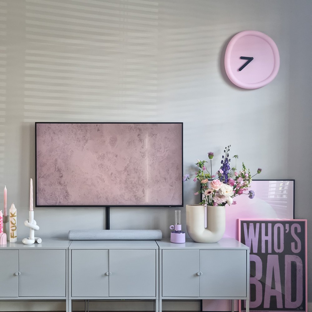Modern living room with a TV, decorative items, and a clock on the wall.
