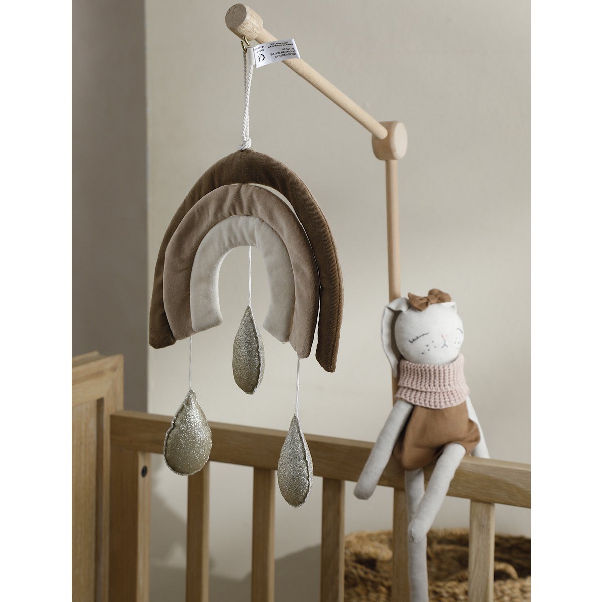 Children's mobile with rainbow and cloud design hanging above a crib.
