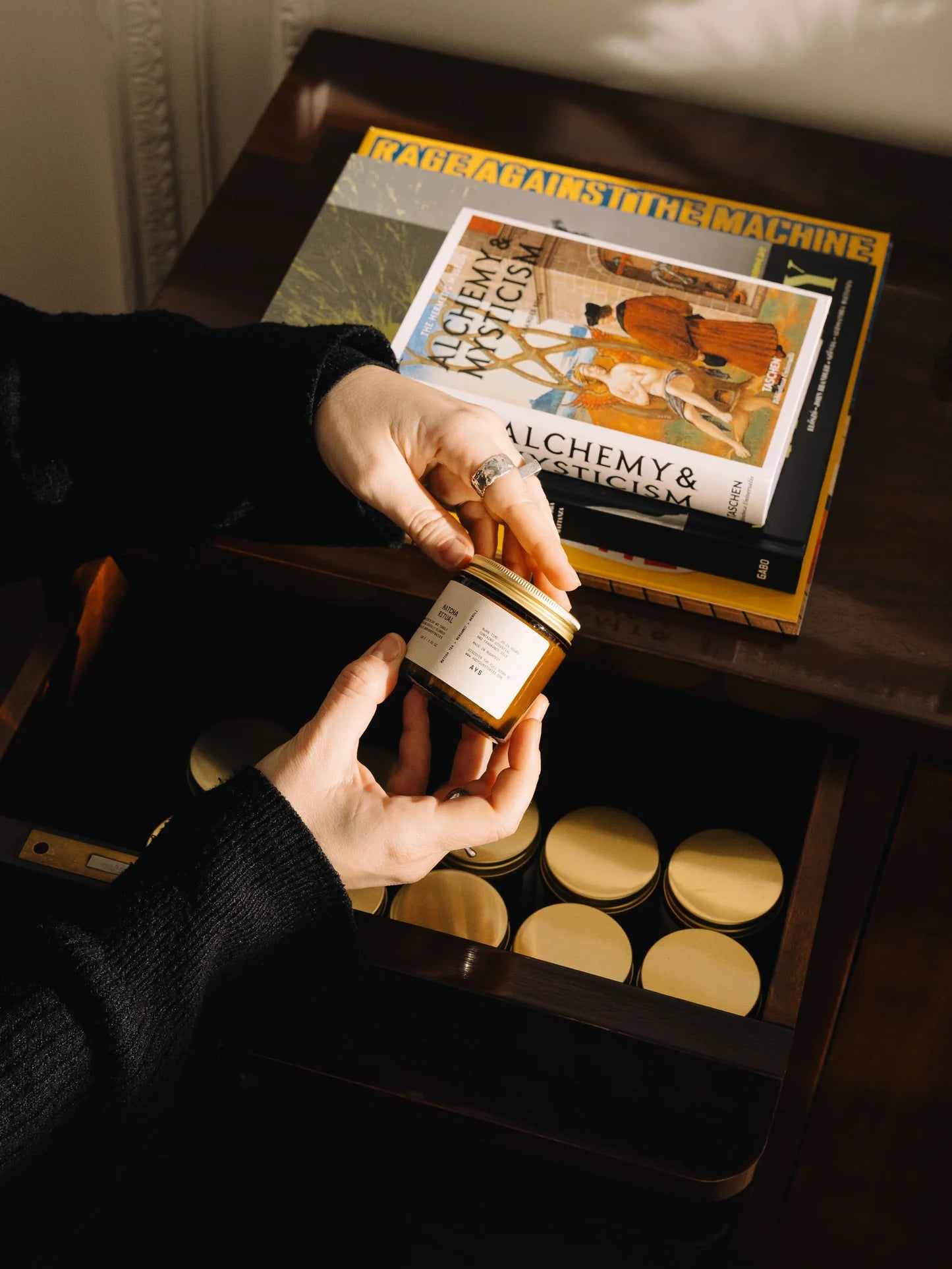 Person holding a wax candle
with a book titled 'The Alchemist' in the background.