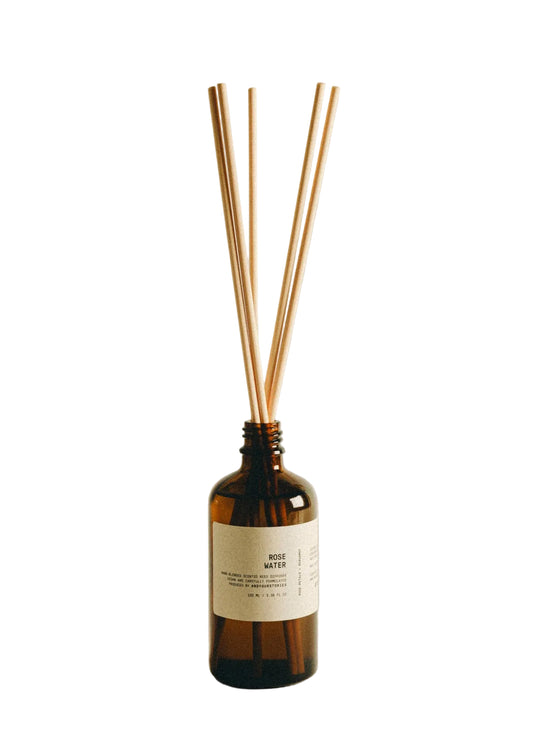Brown diffuser bottle with wooden sticks on a beige background