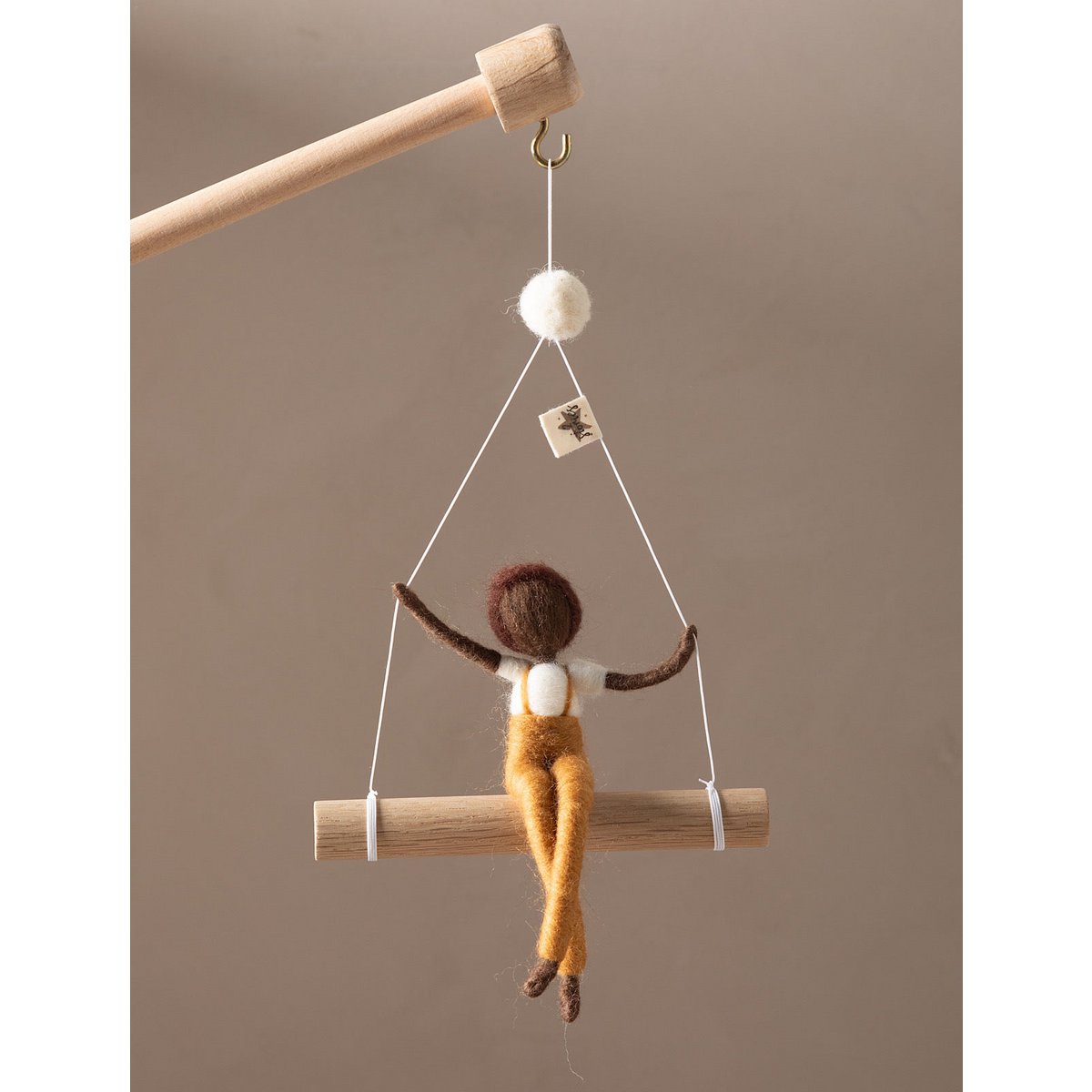 Decorative hanging figure on a wooden stick against a brown background