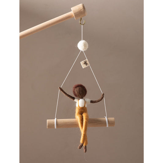 Decorative hanging figure on a wooden stick against a brown background