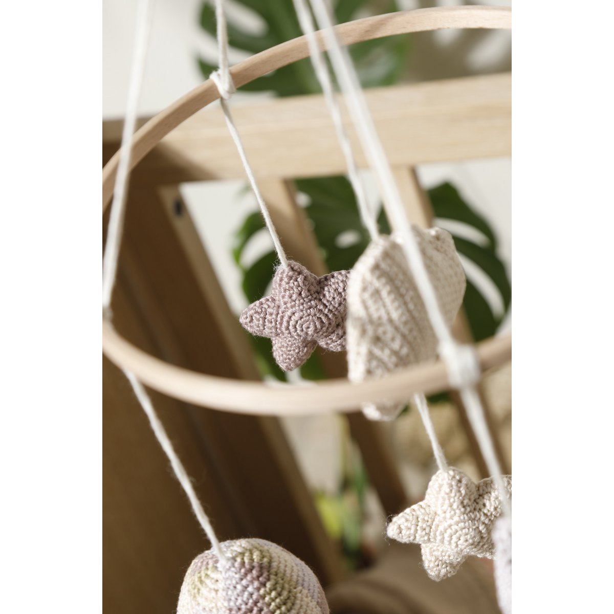 Decorative hanging mobile with star-shaped crochet elements on a blurred background