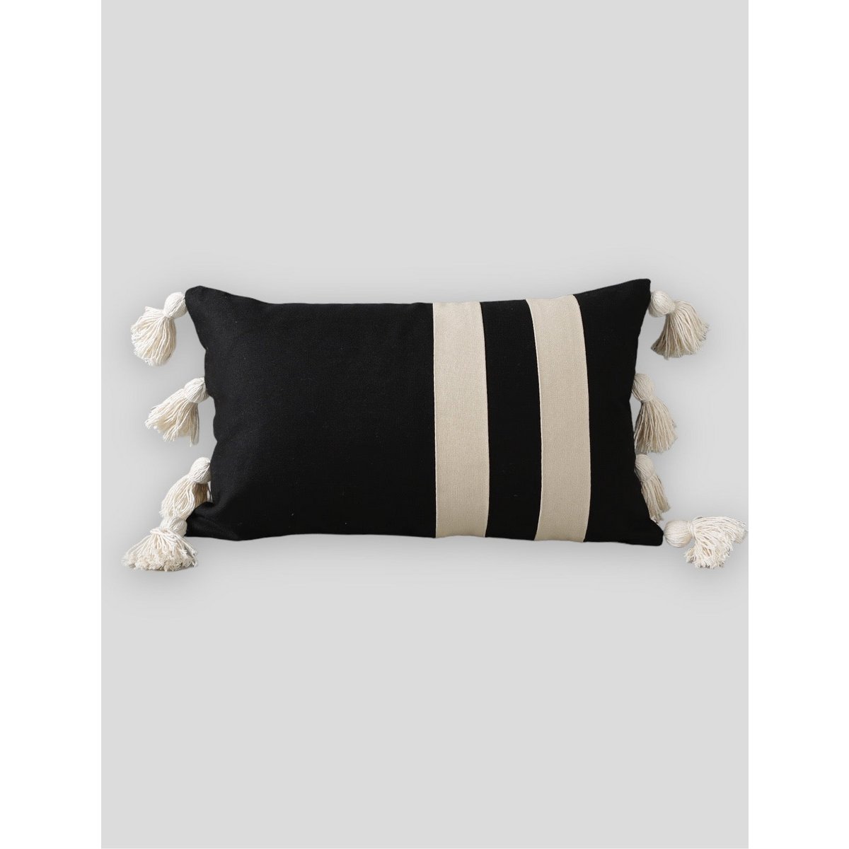 Black and beige striped pillow with tassels on a light gray background