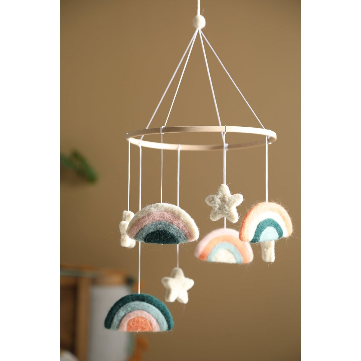 Decorative mobile with rainbow and star shapes hanging against a neutral background