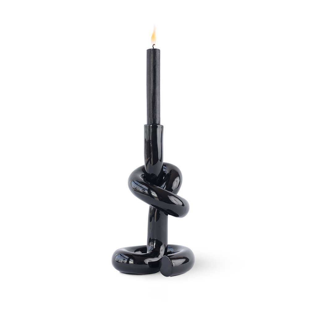 Black knot-shaped candle holder with a lit candle on a white background