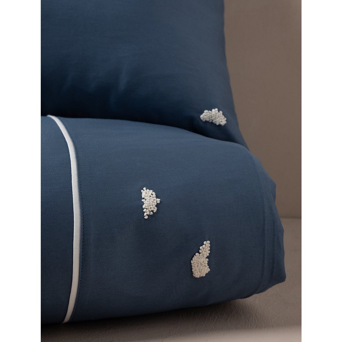 Navy blue pillow with decorative white elements on a neutral background