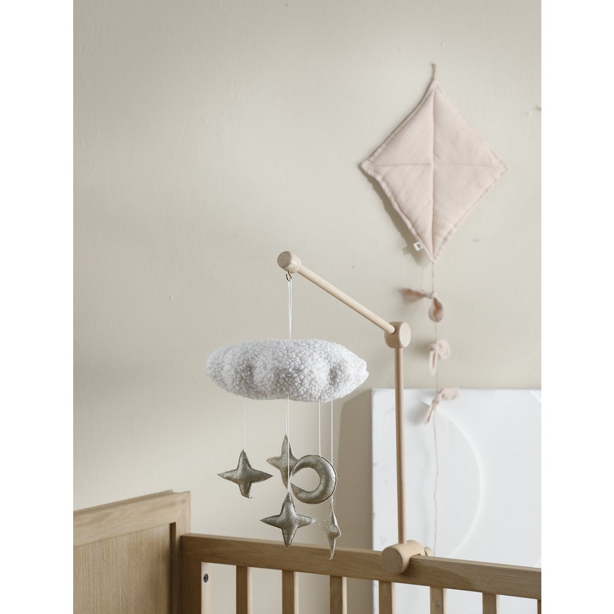 Baby crib with mobile and decorative elements against a plain wall