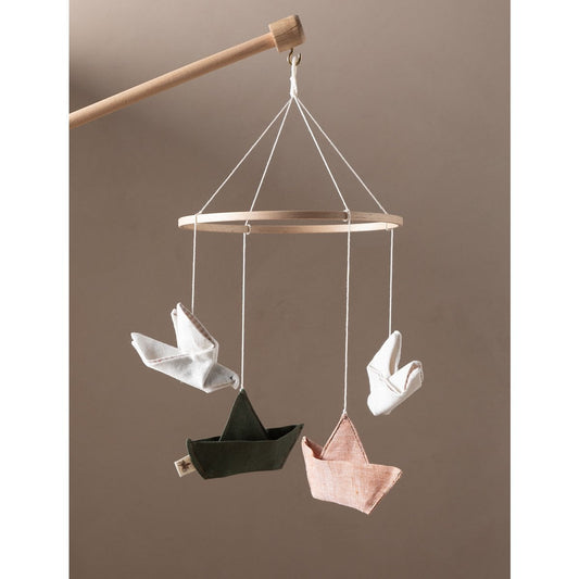 Hanging mobile with paper boat and bird shapes on a plain background