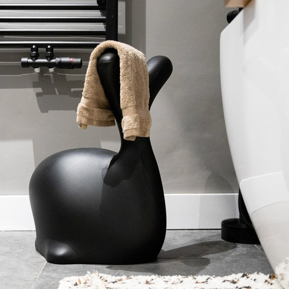 Black stool with a beige towel draped over it in a bathroom setting