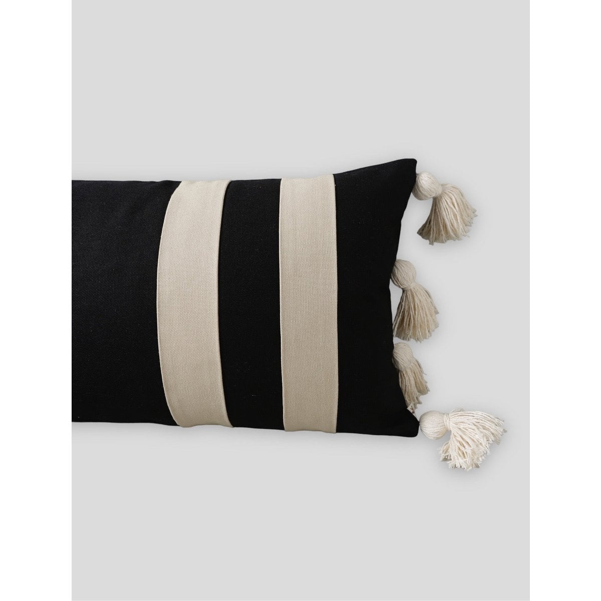 Black and beige striped pillow with tassels on a white background