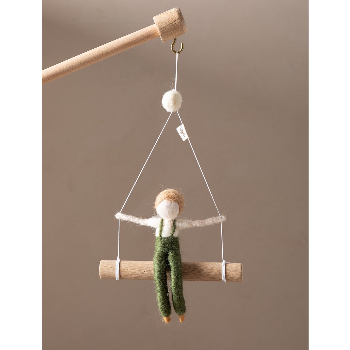 Small figurine of a person on a swing against a plain background