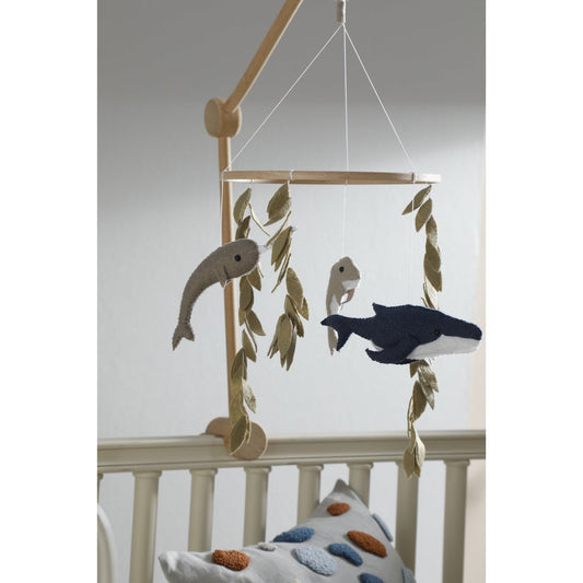 Baby crib mobile with fish and whale design hanging above a crib.