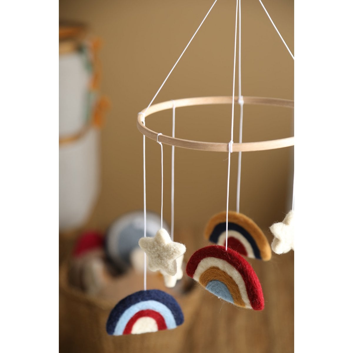 Decorative mobile with rainbow and star shapes hanging from a circular frame.