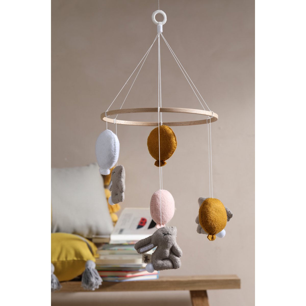 Children's mobile with hanging toys on a wooden surface against a neutral wall.