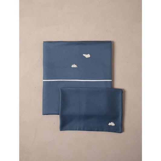 Two blue satin pillowcases with cloud designs on a beige background