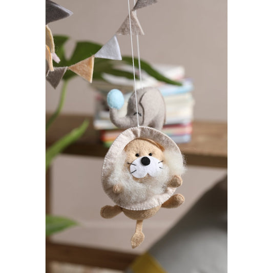 Hanging plush toy of a hedgehog with a shell on a string, set against a blurred indoor background.