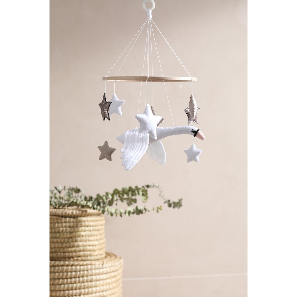 Decorative mobile with stars and a whale hanging against a beige wall.
