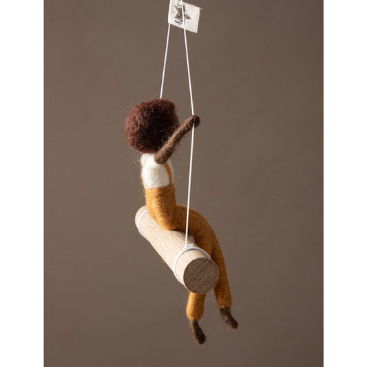 Textile art of a child climbing a rope with a brown background