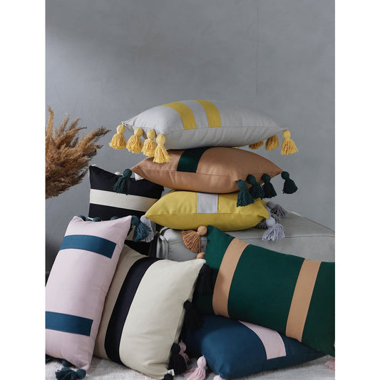 Stack of colorful pillows with tassels on a neutral background