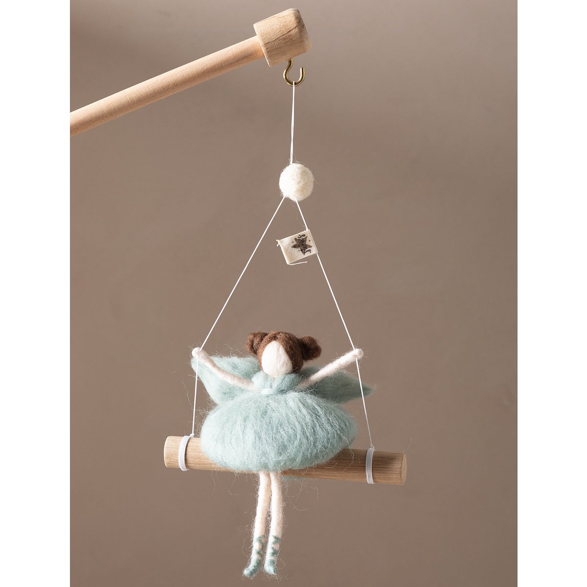 Decorative hanging figure on a wooden stick against a beige background