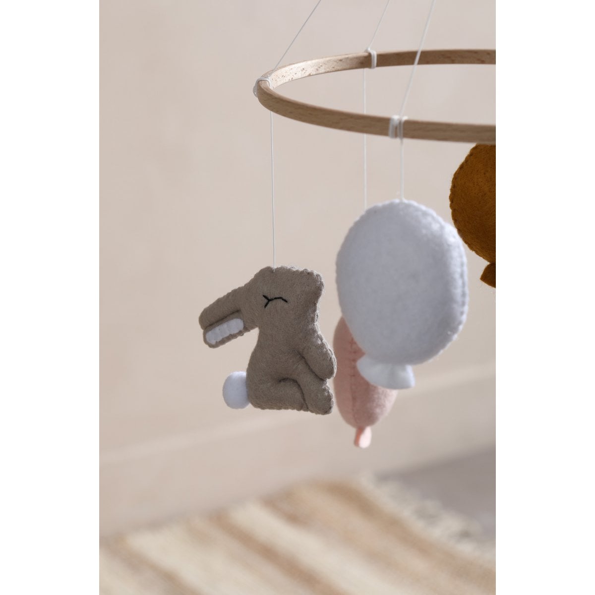 Baby mobile with plush toys hanging from a wooden ring against a neutral background