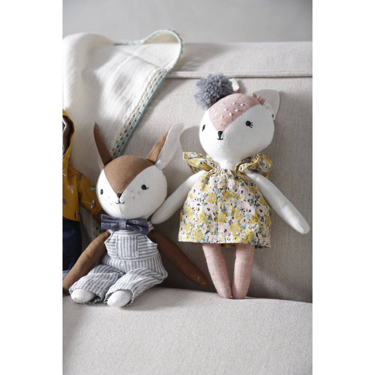 Two plush toys, one rabbit and one bear-like creature, sitting on a light-colored surface.