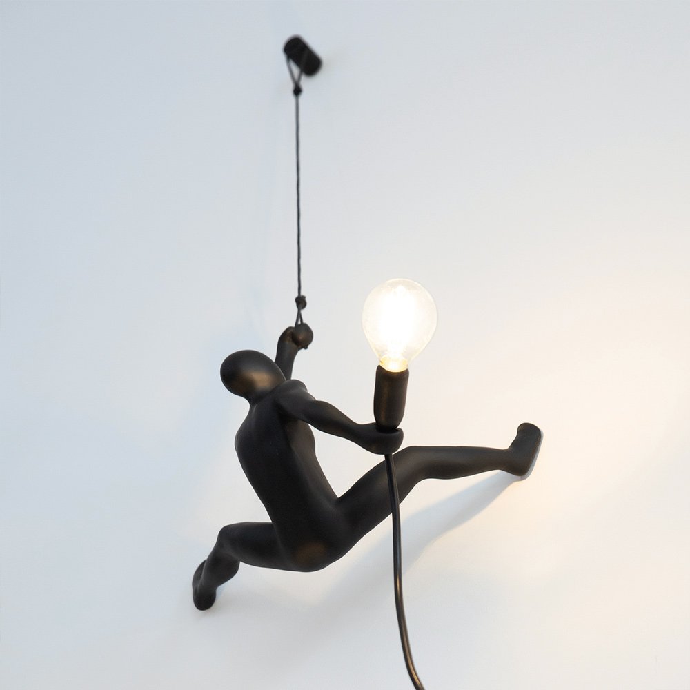 Black figure climbing a rope with a light bulb as a head, against a white background