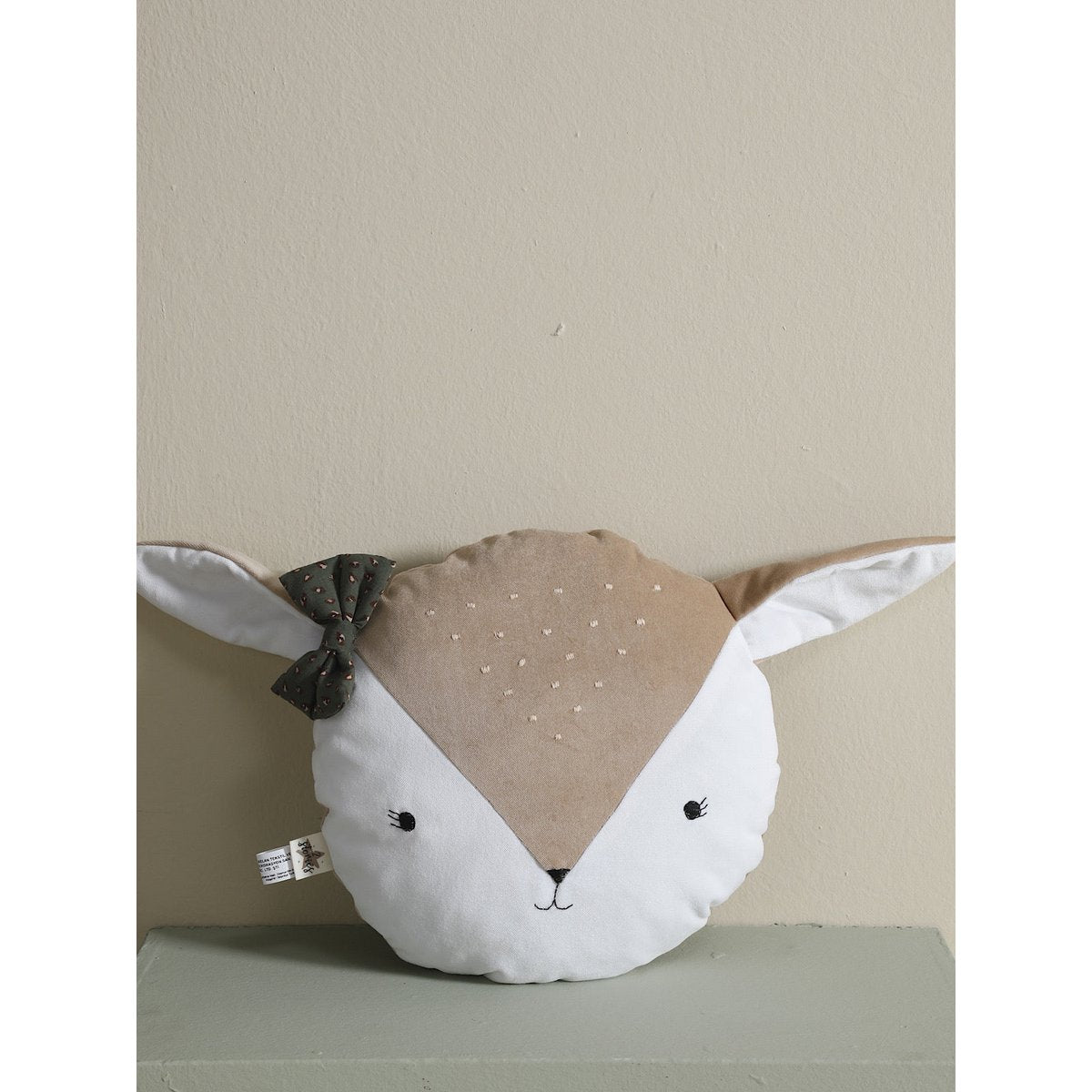 Fox-shaped pillow with a bow on a neutral background