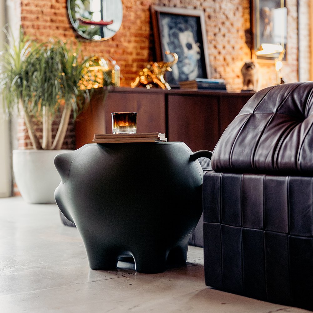 Modern living room with a black pig-shaped side table and leather sofa.