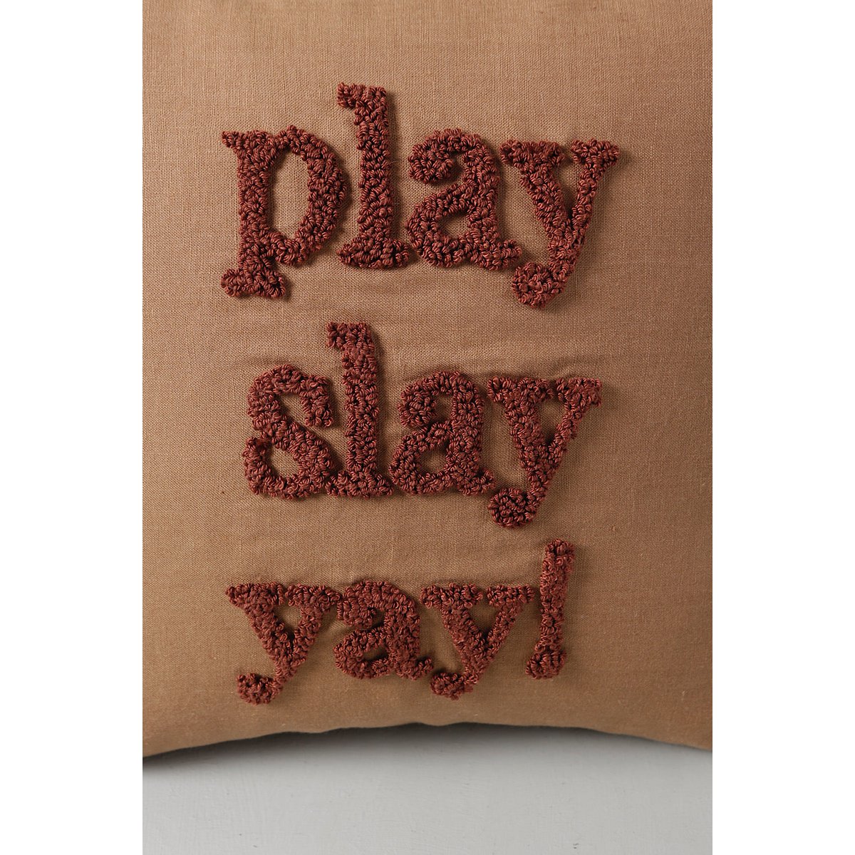 Brown pillow with 'play slay yay!' text on a white background