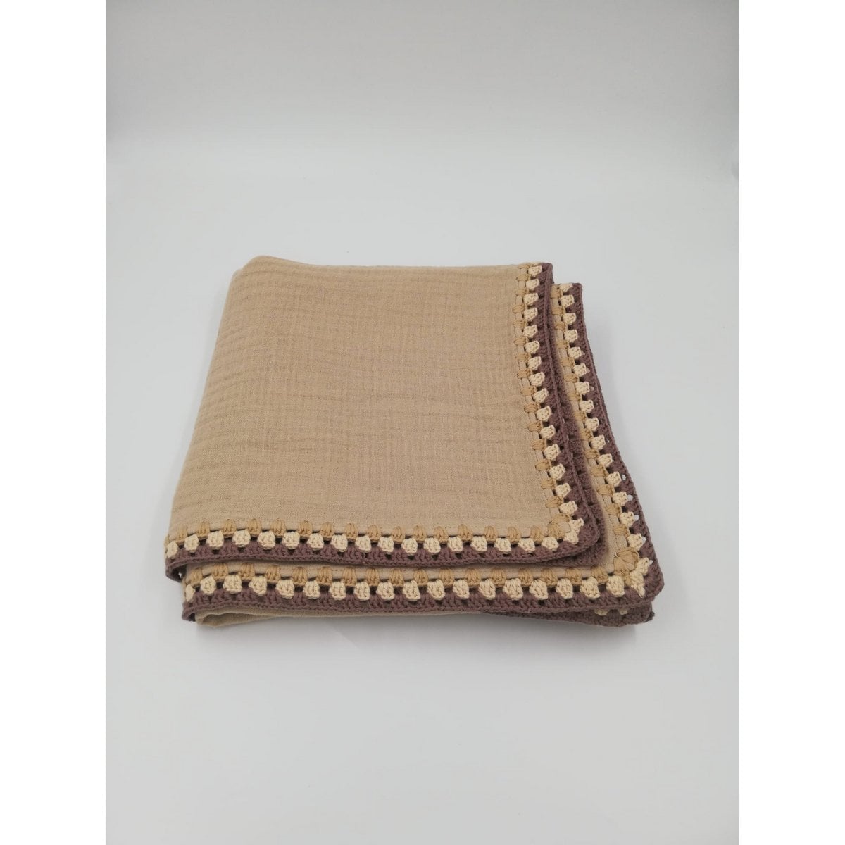 Folded fabric blanket with brown border on a light gray background