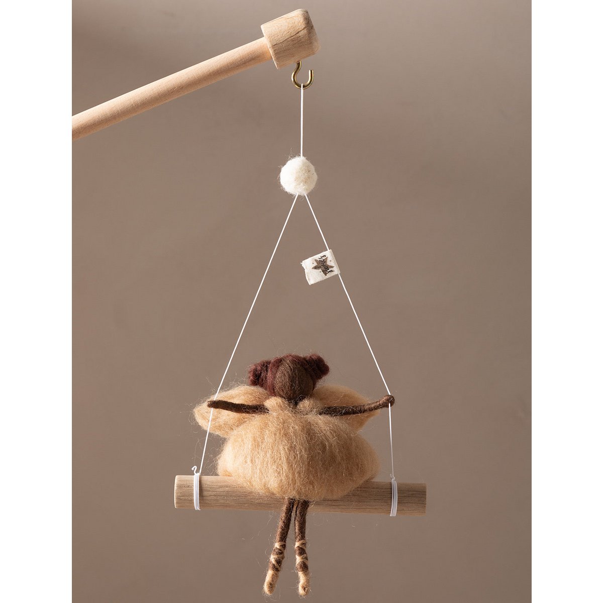Decorative hanging figure on a swing against a beige background