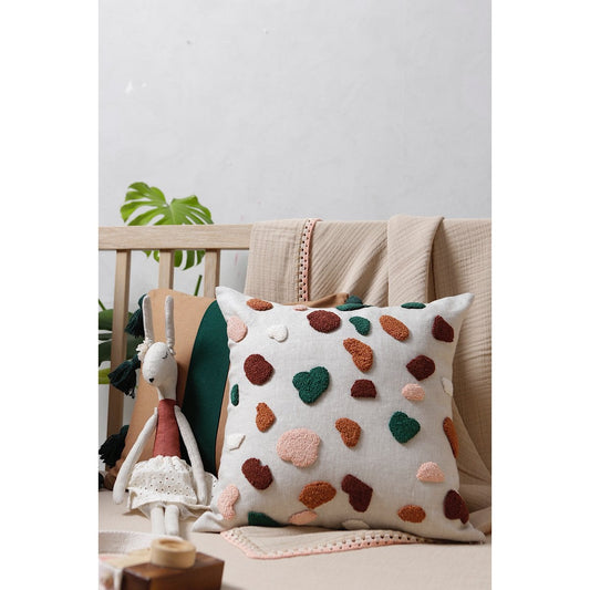 Decorative pillow with colorful patterns on a couch next to a plush toy