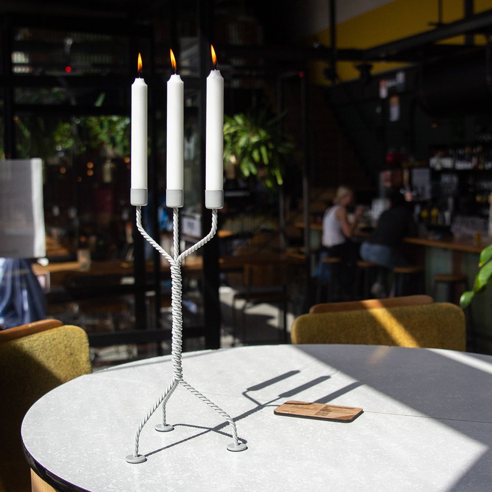 Candle holder with three lit candles on a table in a restaurant setting