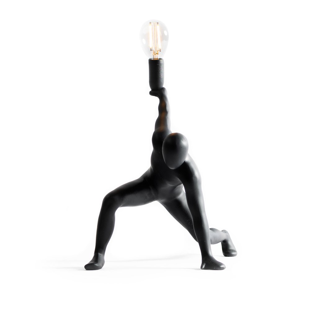 Black abstract sculpture holding a light bulb on a white background