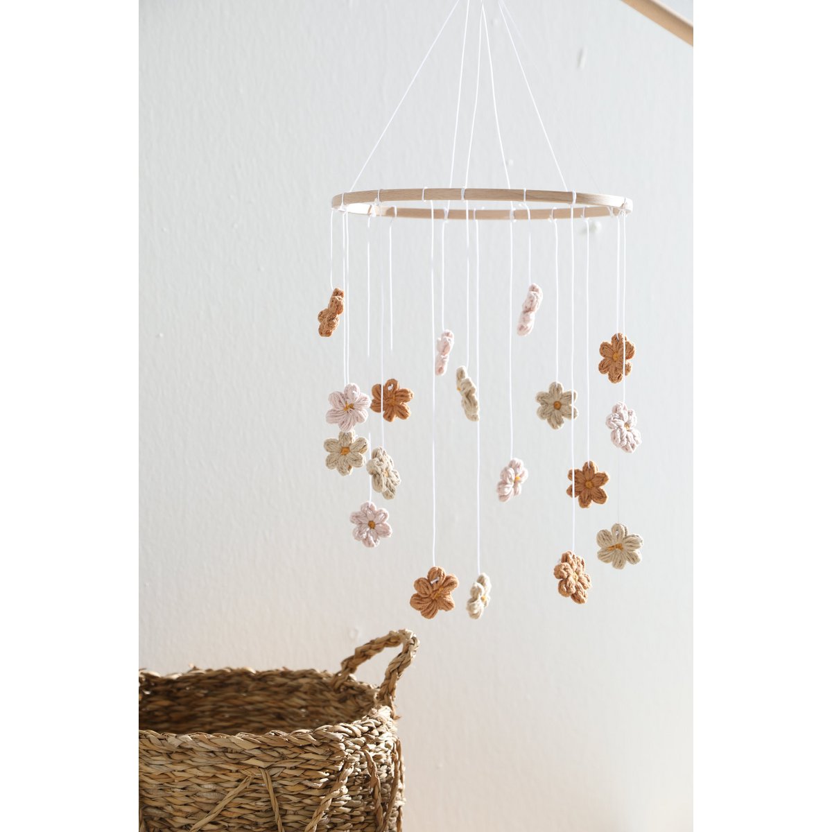 Decorative flower mobile hanging above a woven basket on a white background