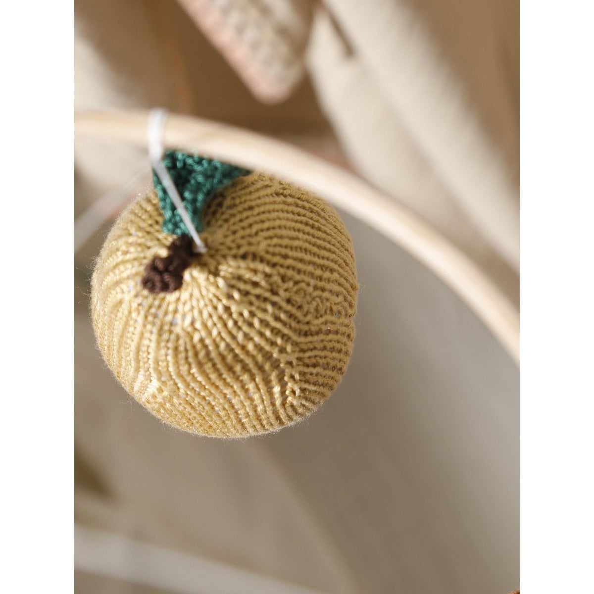 Textured round object with a green top and brown stem on a neutral background