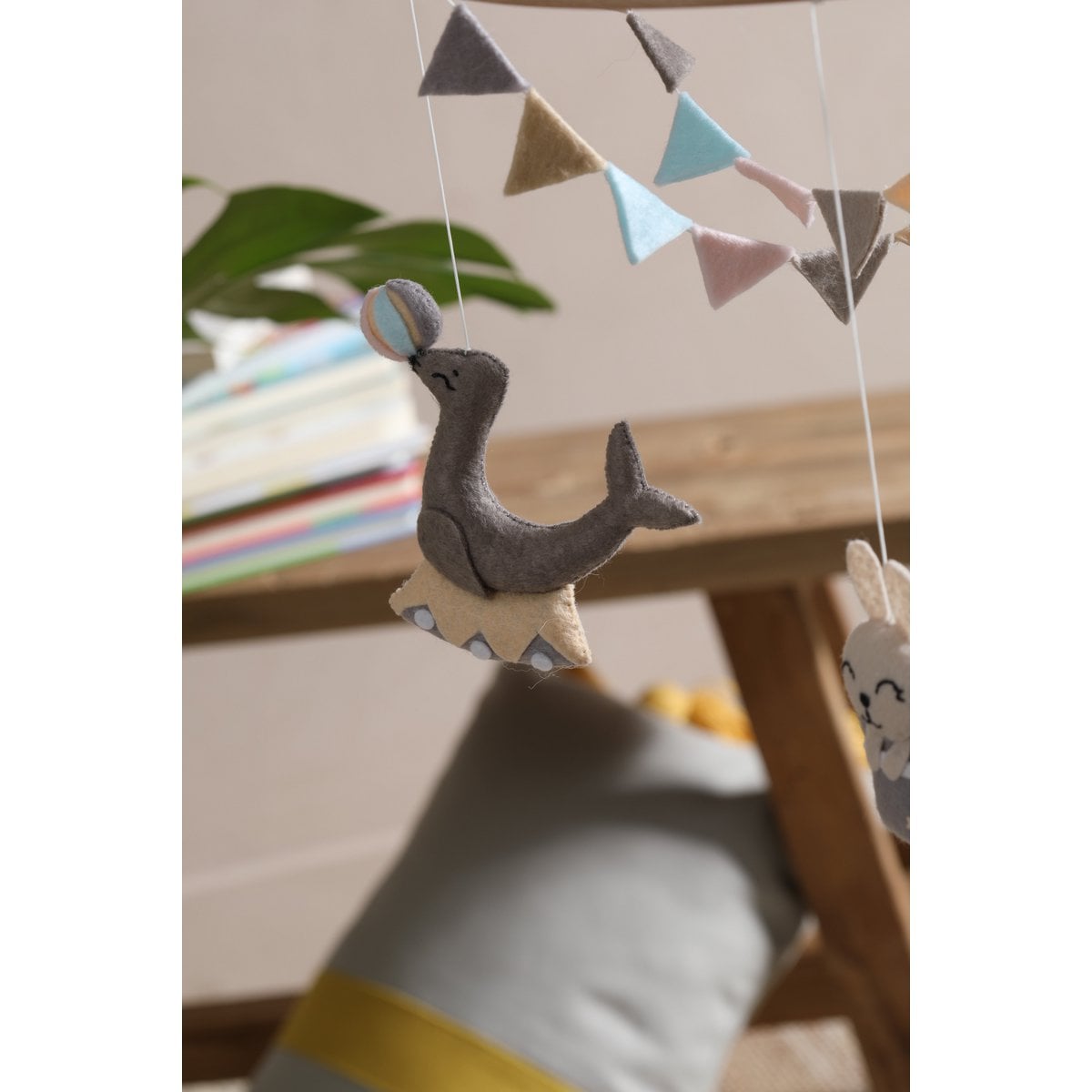 Decorative mobile with animal shapes and colorful flags hanging above a wooden shelf.