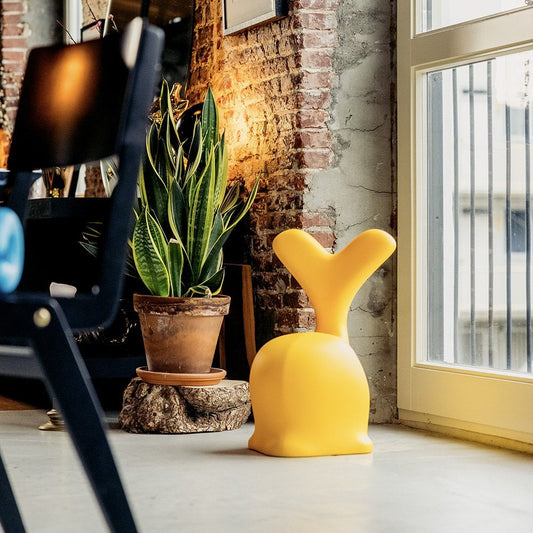 Yellow decorative object and potted plant on a windowsill with a brick wall background