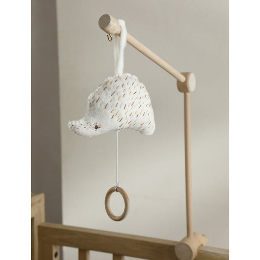Baby mobile with textured ball and wooden ring hanging from a wooden stand against a neutral background